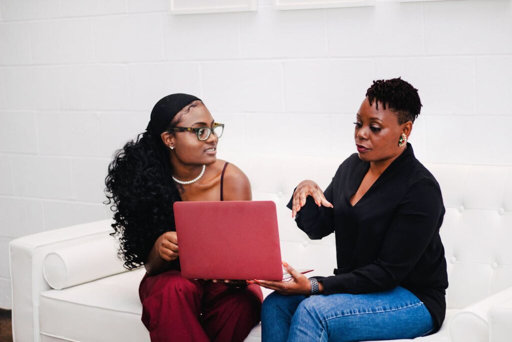 two women sitting on a couch sharing a laptop-benefits of a website for small business
