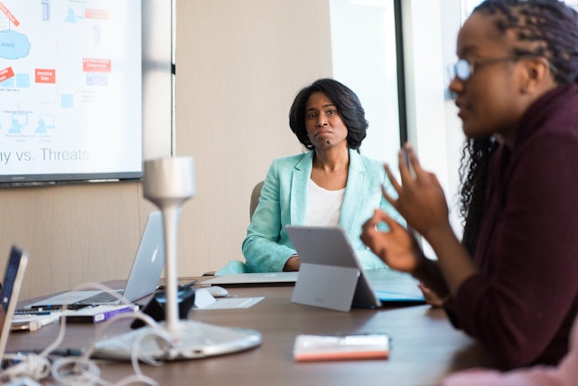 two women in a boardroom with one giving a presentation