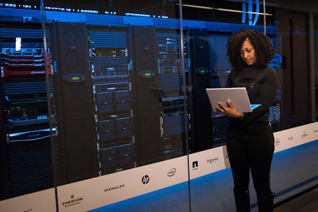 A female software engineer standing beside server racks