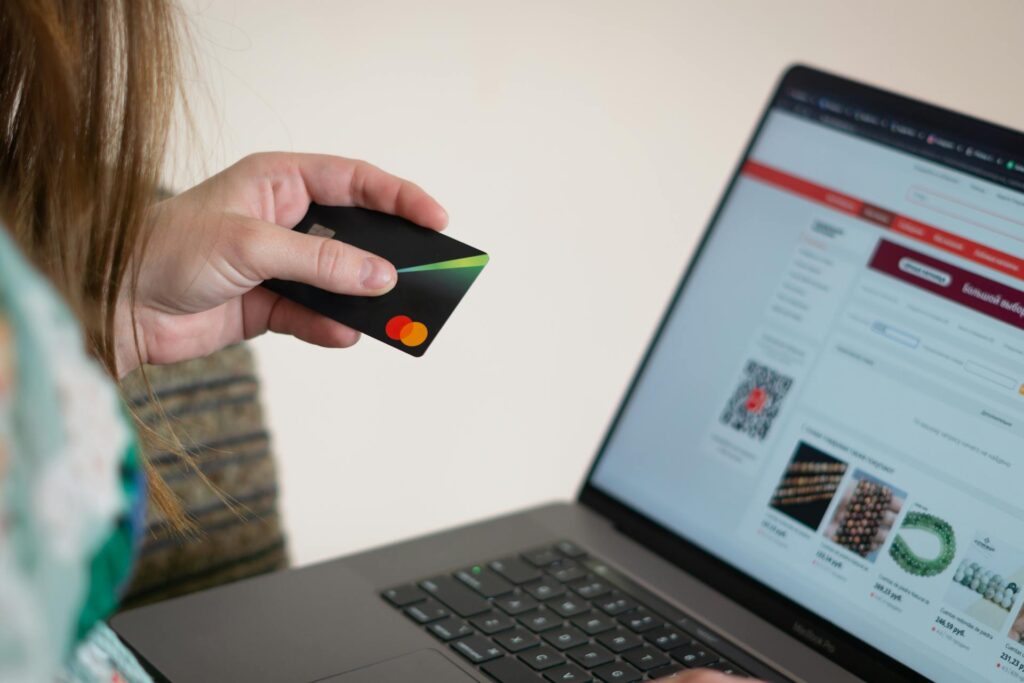 a person holding an atm card while

typing on her laptop