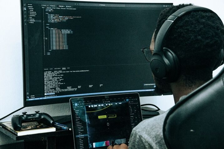 A man sitting in front of a computer wearing headphones