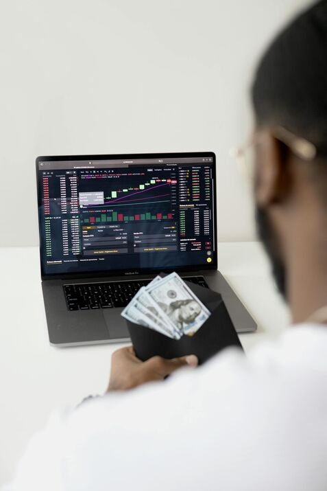 A man in front of a laptop with a visible wad of cash