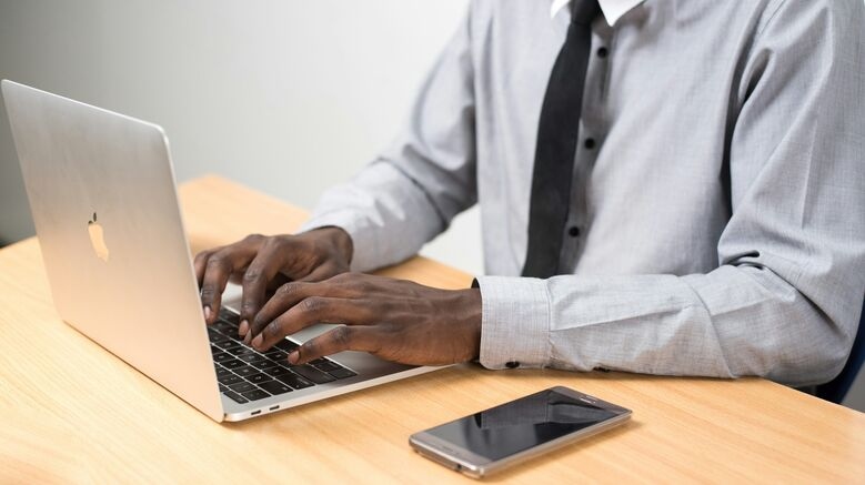 a man sits typing on a MacBook Air at a table