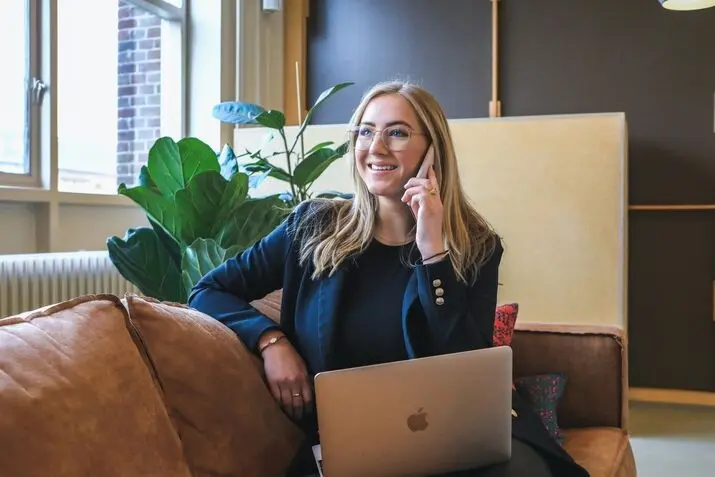 a white lady making call with macbook on your lap
