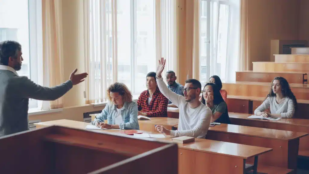 students raising hands in-a lecture hall classroom